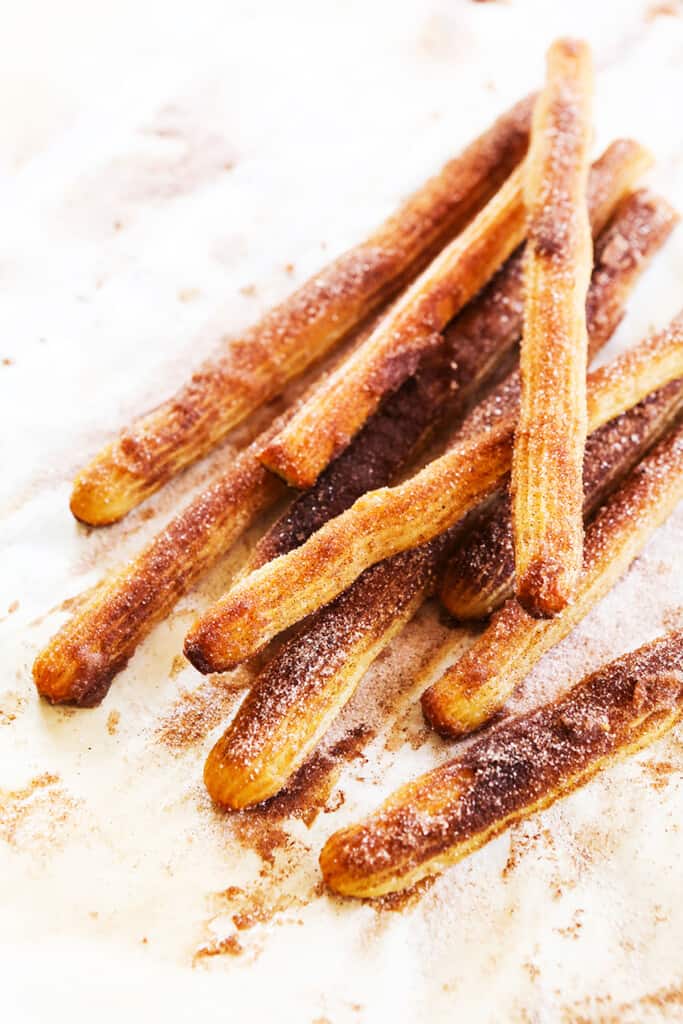 Baked churros covered in cinnamon and sugar stacked on top of one another. 