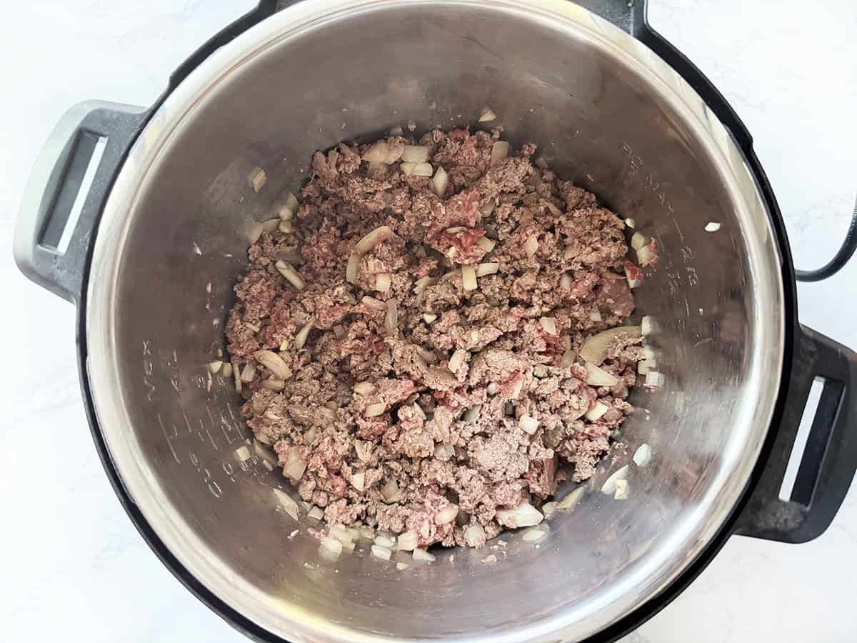 Cooked ground beef mixture in a pressure cooker.