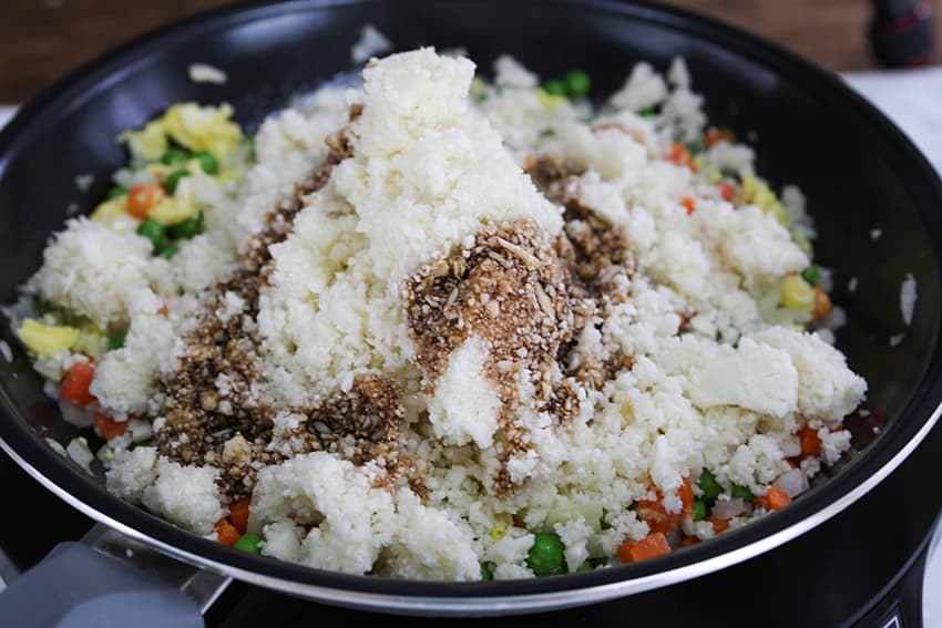 pureed cauliflower in skillet with soy sauce and veggies
