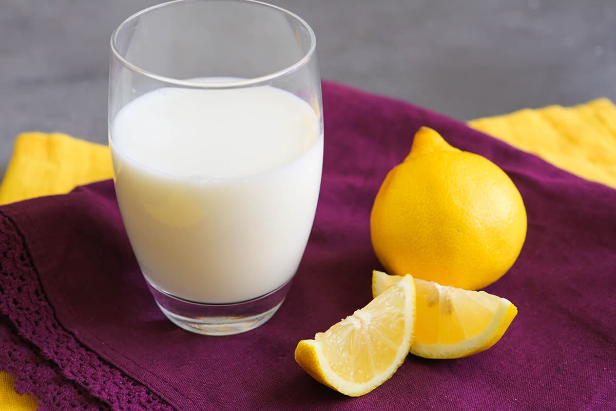 A glass of buttermilk next to lemon slices.