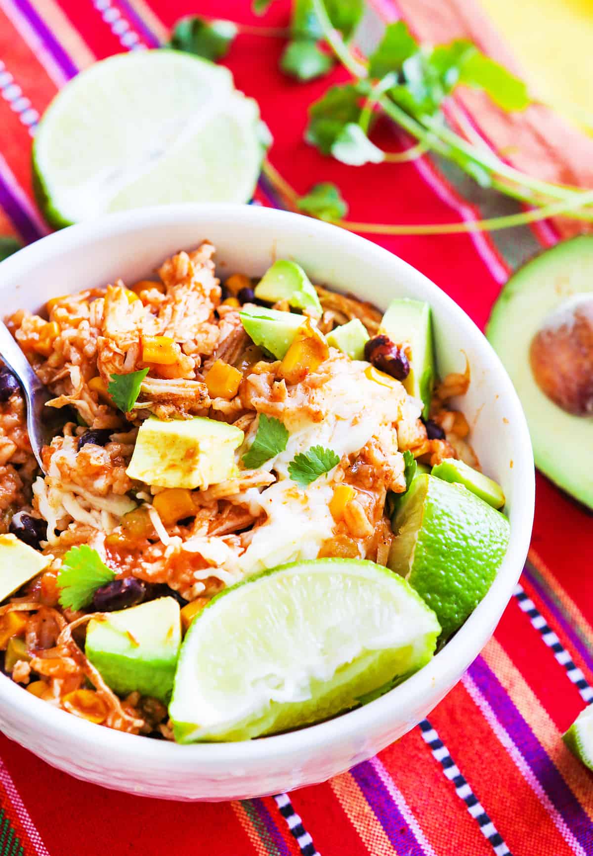 Chipotle Chicken Bowl with avocados and lime wedges inside.