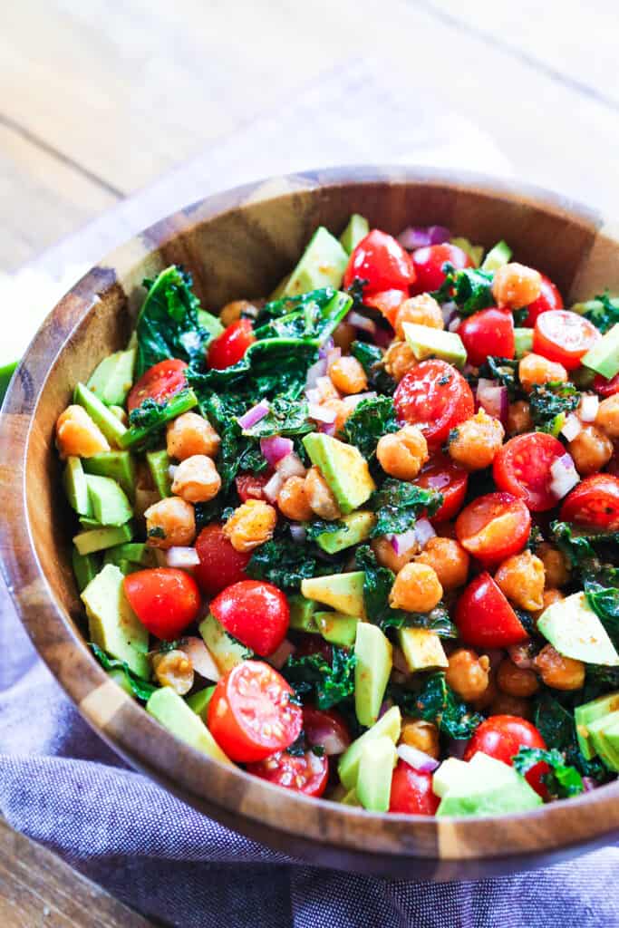 Kale salad with chickpeas in a big wooden salad bowl. 