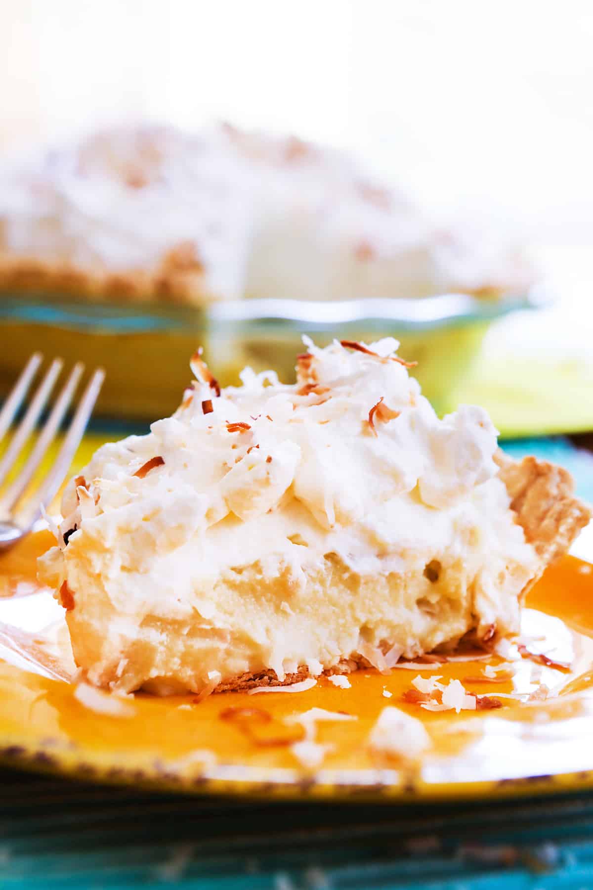A slice of coconut cream pie on a yellow plate.