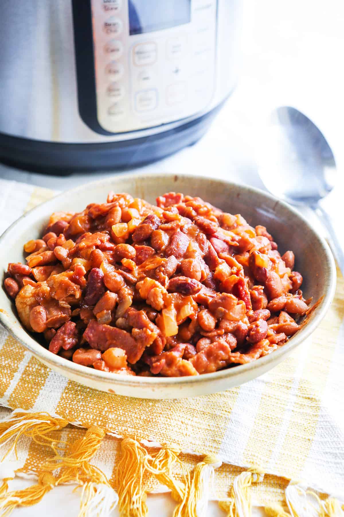 Steaming bowl of cooked baked beans in front of Instant Pot. 