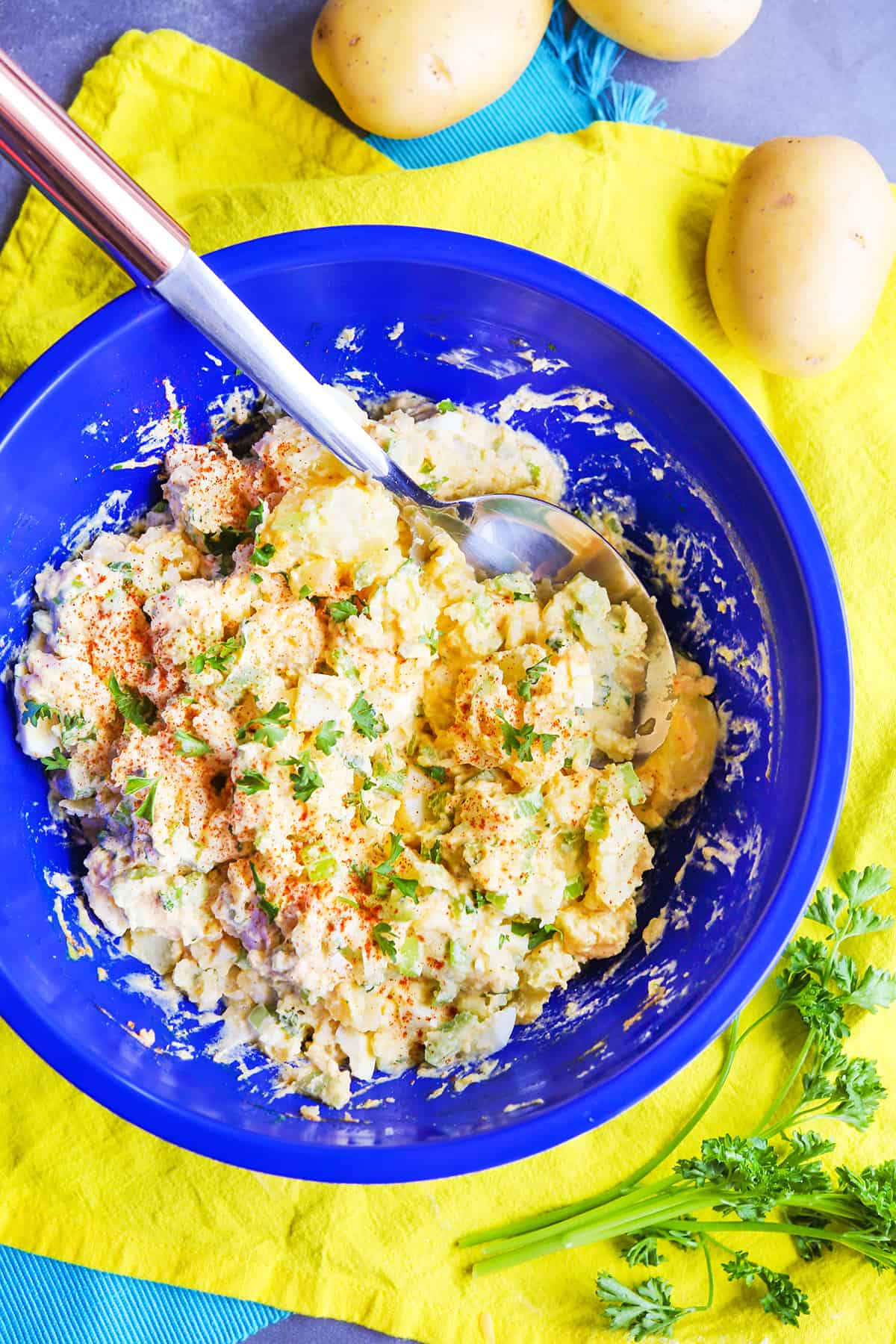 Looking down into a blue mixing bowl filled with potato salad.