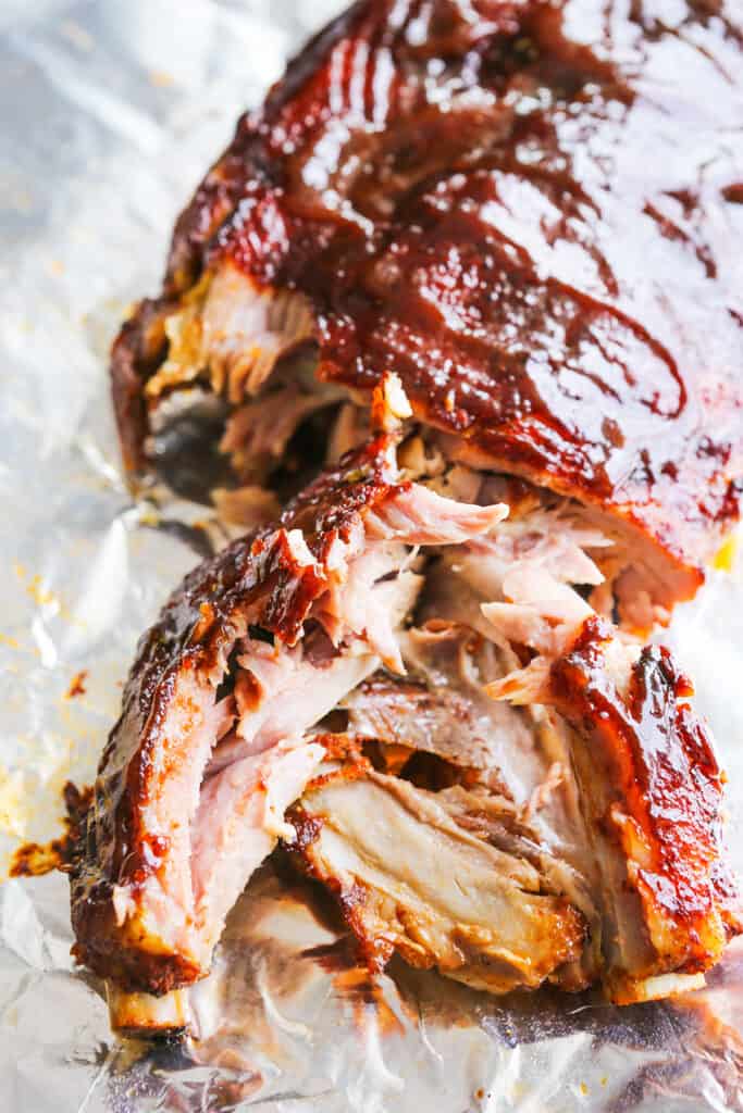 Parchment paper topped with instant pot ribs that has a healthy slather of BBQ sauce over them. 