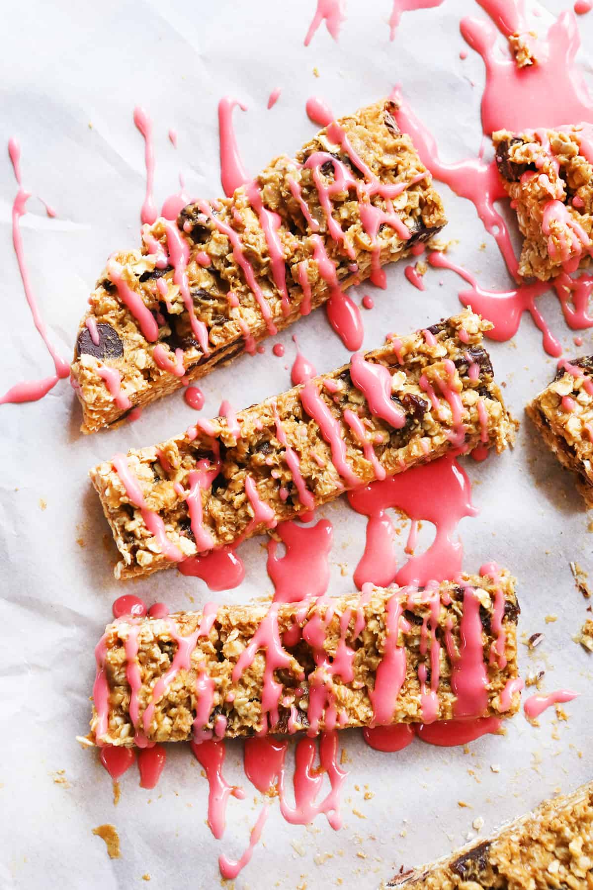 top view of three granola bars lined up on parchment and drizzled with icing