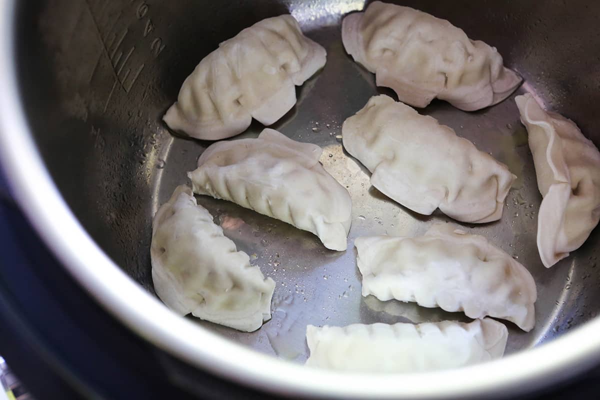 Frozen dumplings lined up in an air fryer.