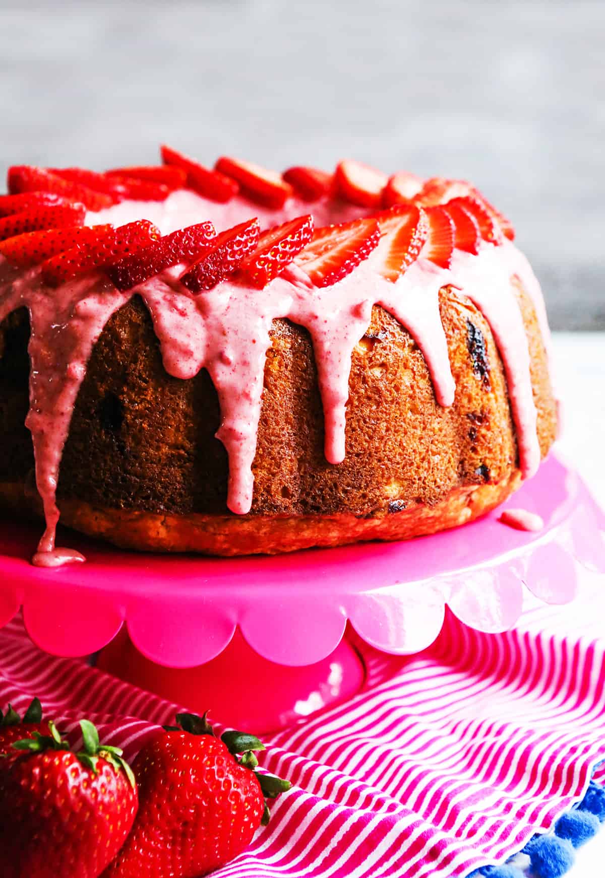 Side view of strawberry bundt cake topped with fresh strawberries.