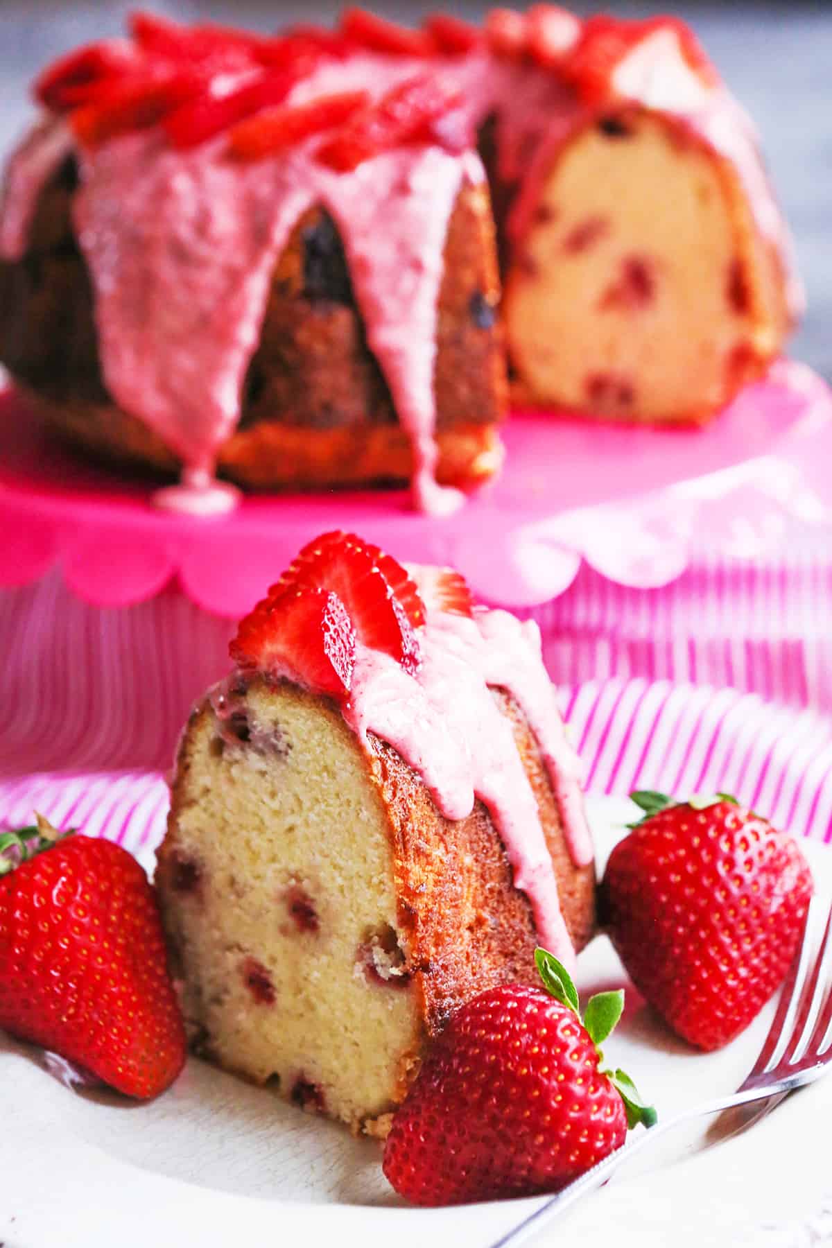 Perfect slice of strawberry bundt cake with frosting and strawberries on top.