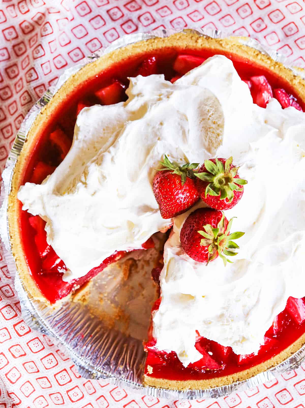 Top view of a strawberry pie topped with whipped cream and strawberries.