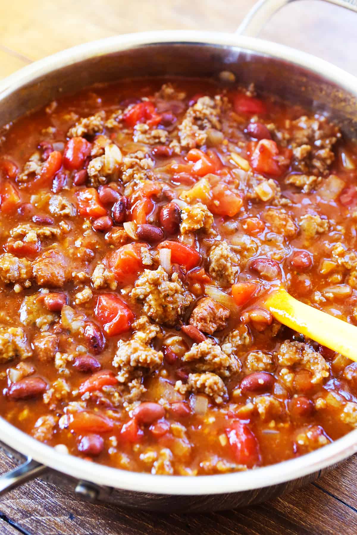 Skillet filled with chili with a serving spoon inside.