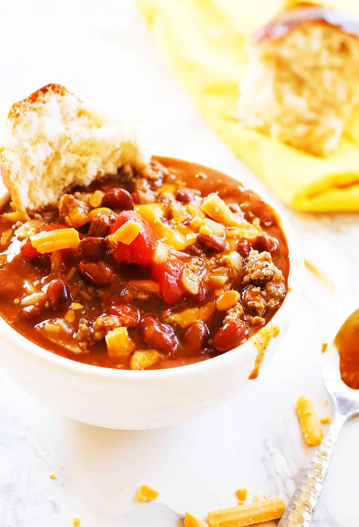Serving of chili in a bowl with half of a bun inside.