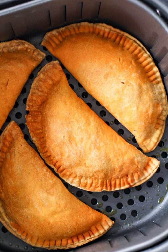 air fryer basket with cheesy beef pastellito sitting inside