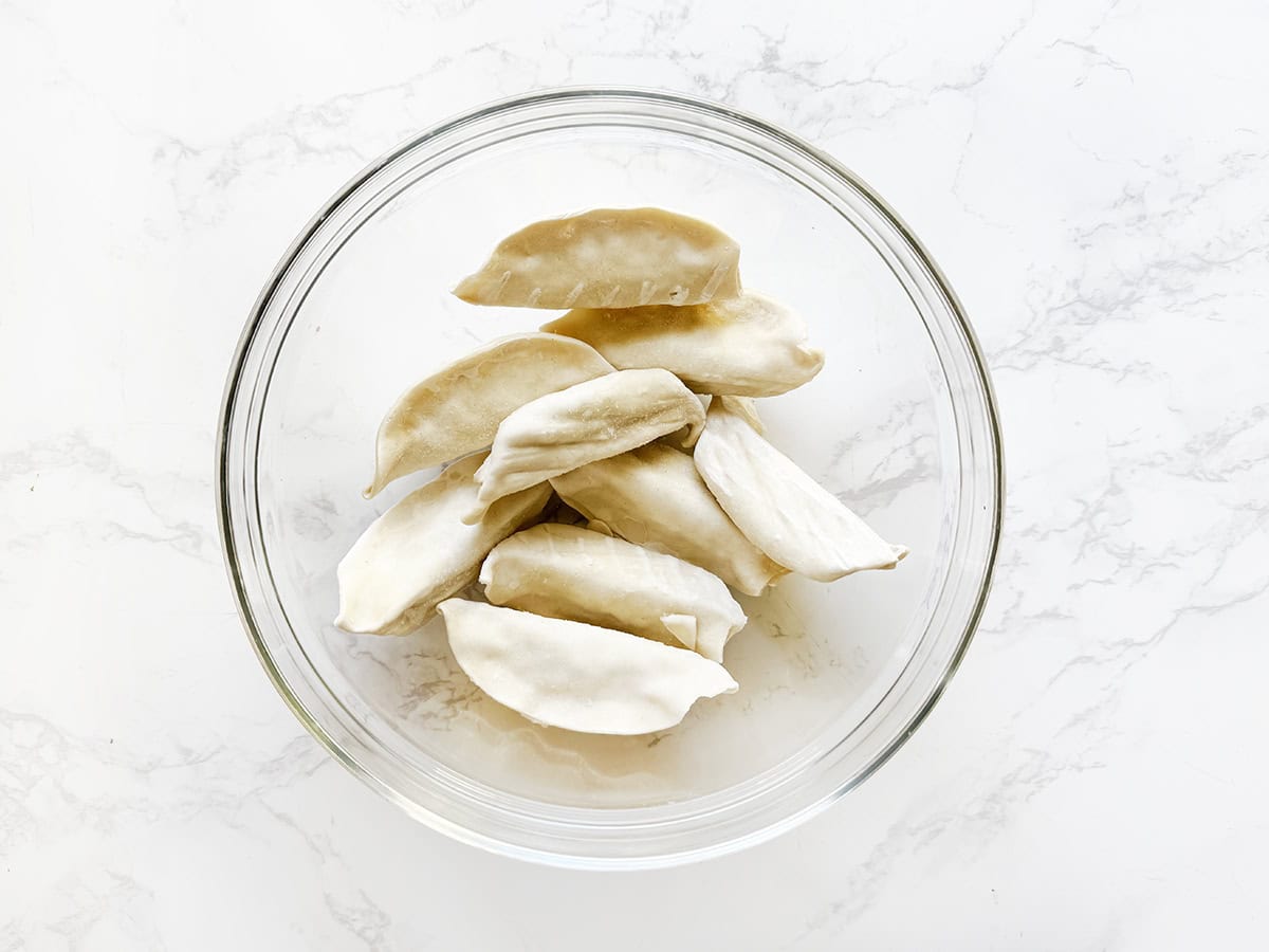 Glass bowl with frozen dumplings inside.