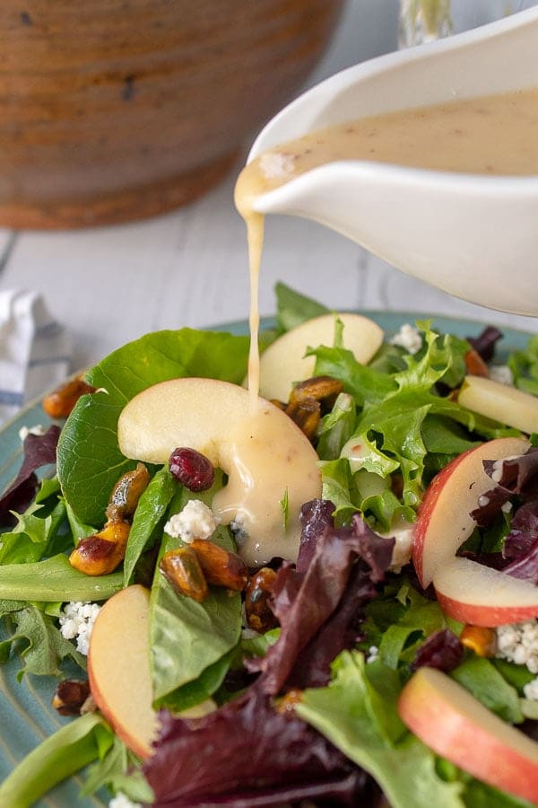 plate of harvest salad with dressing being drizzled over it