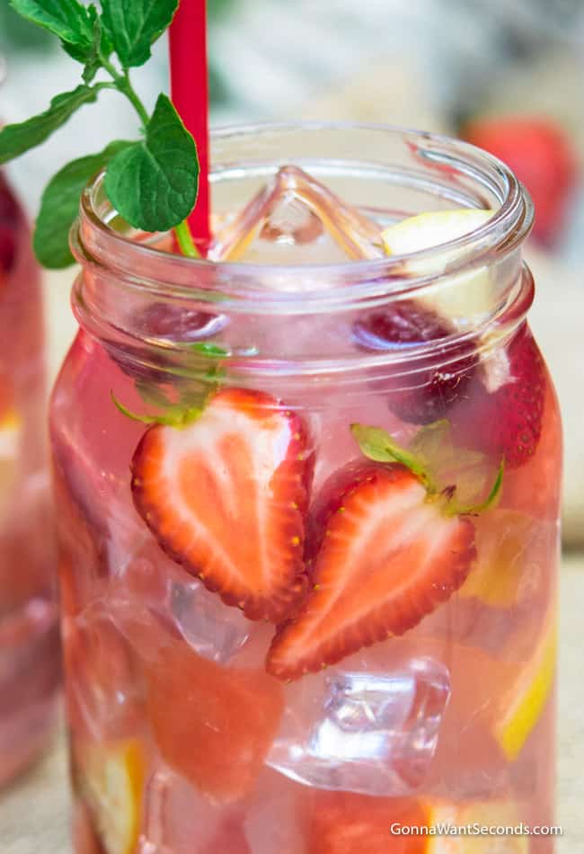 hippie juice in a mason jar with slices of fresh fruit and a herb garnish