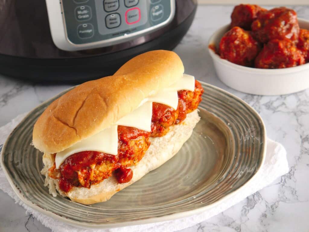 a turkey meatball sub on a plate next to an instant pot