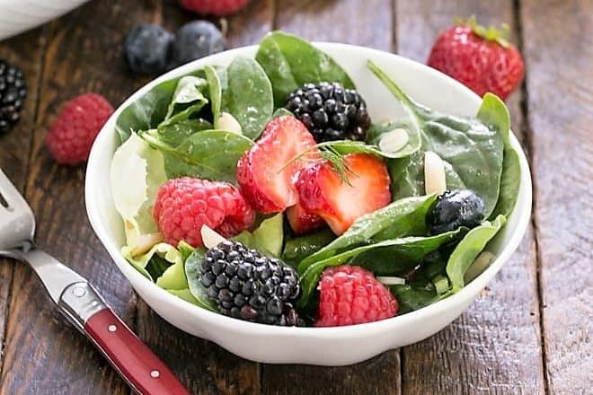 green salad with berries in a white bowl