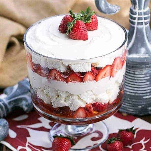 layers of strawberry trifle in a glass container with whole fresh strawberries arranged on top