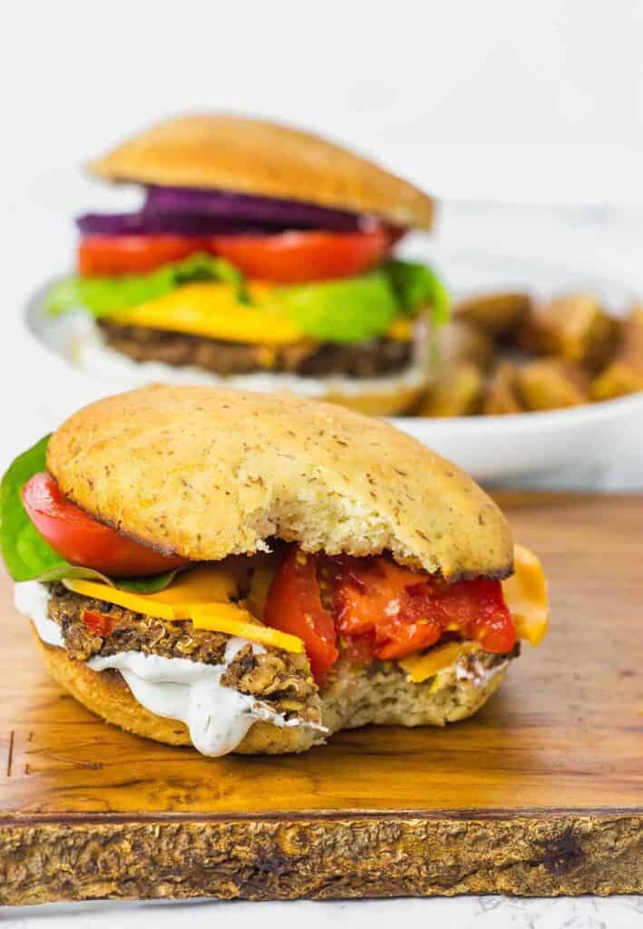 black bean quinoa burger sitting on a board with a bite out of it and sauce dripping out