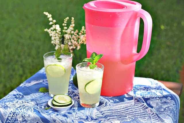 cucumber lime agua fresca in a pitchen sitting next to two glasses filled and a lime garnish