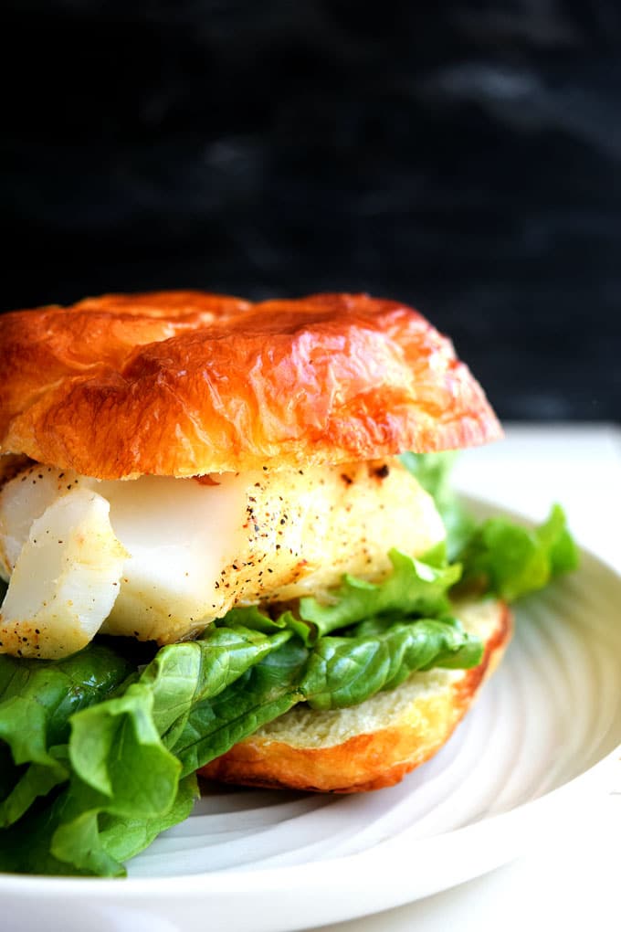 a plate with a cod croissant with lettuce sandwich