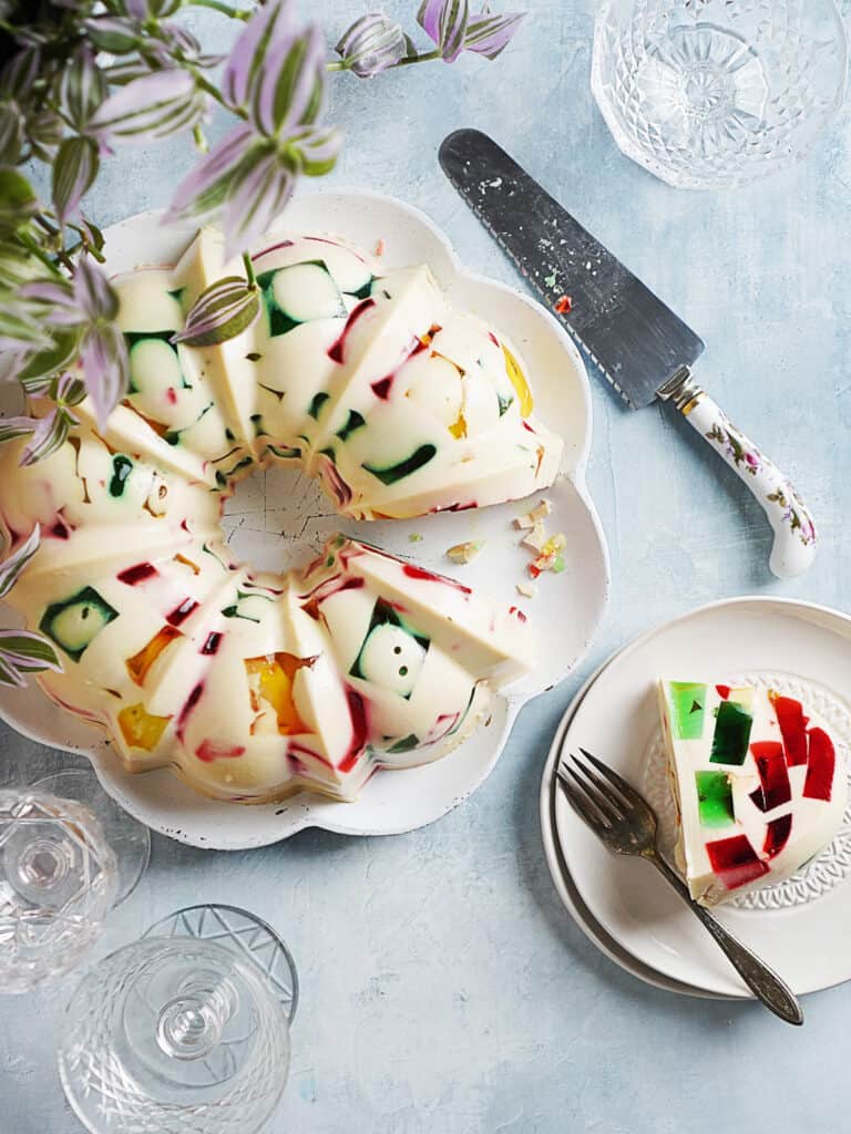 top view of gelatina de mosaico in a bundt form  with a slice removed to a plate next to it. 