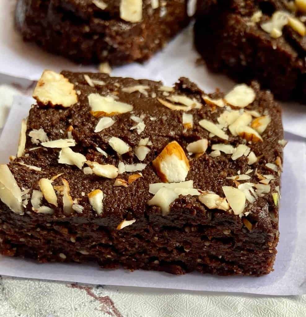 a single slice of no bake brownies with chopped almonds over it sitting on a napkin.