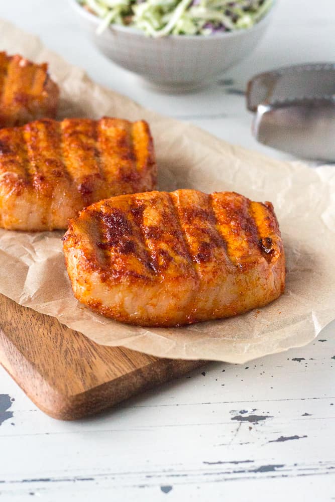 smoked boneless pork chops sitting on a piece of wax paper seasoned and cooked, ready to serve