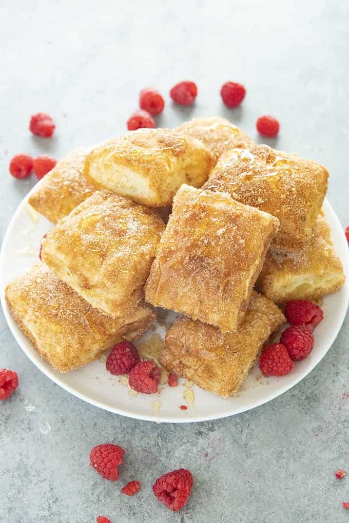 heaping plate of baked sopapillas and fresh raspberries strewn around