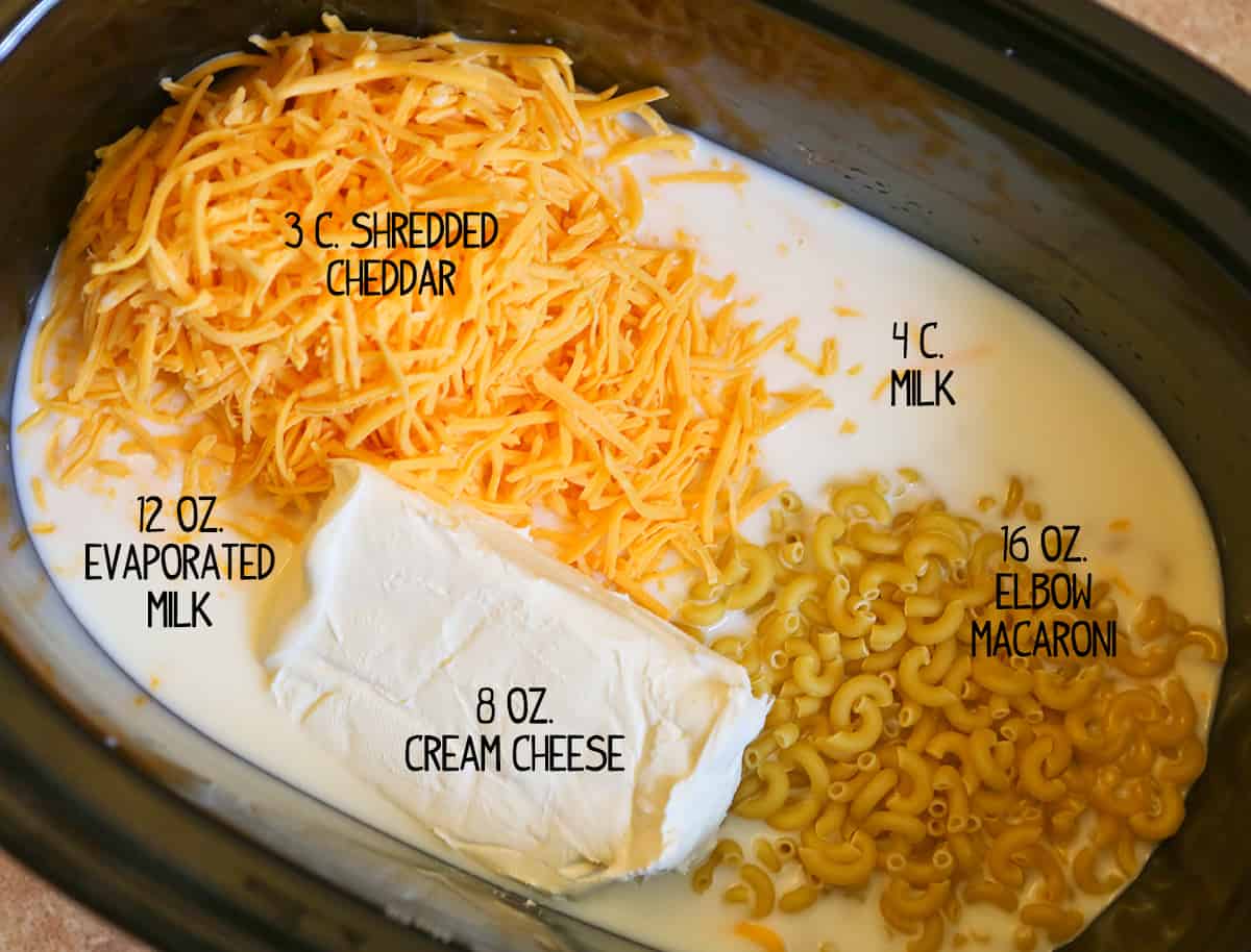 Looking down into a slow cooker filled with ingredients to make a cheesy pasta dish.