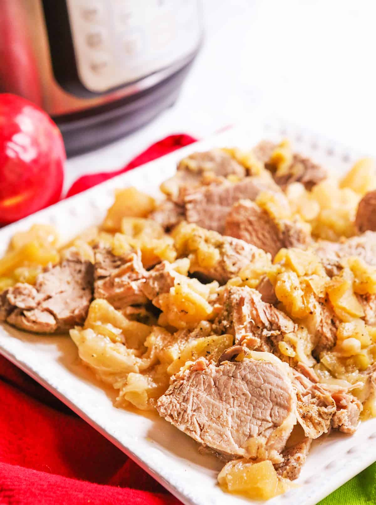 Serving platter with INSTANT POT pork and apples sitting by Instant Pot.