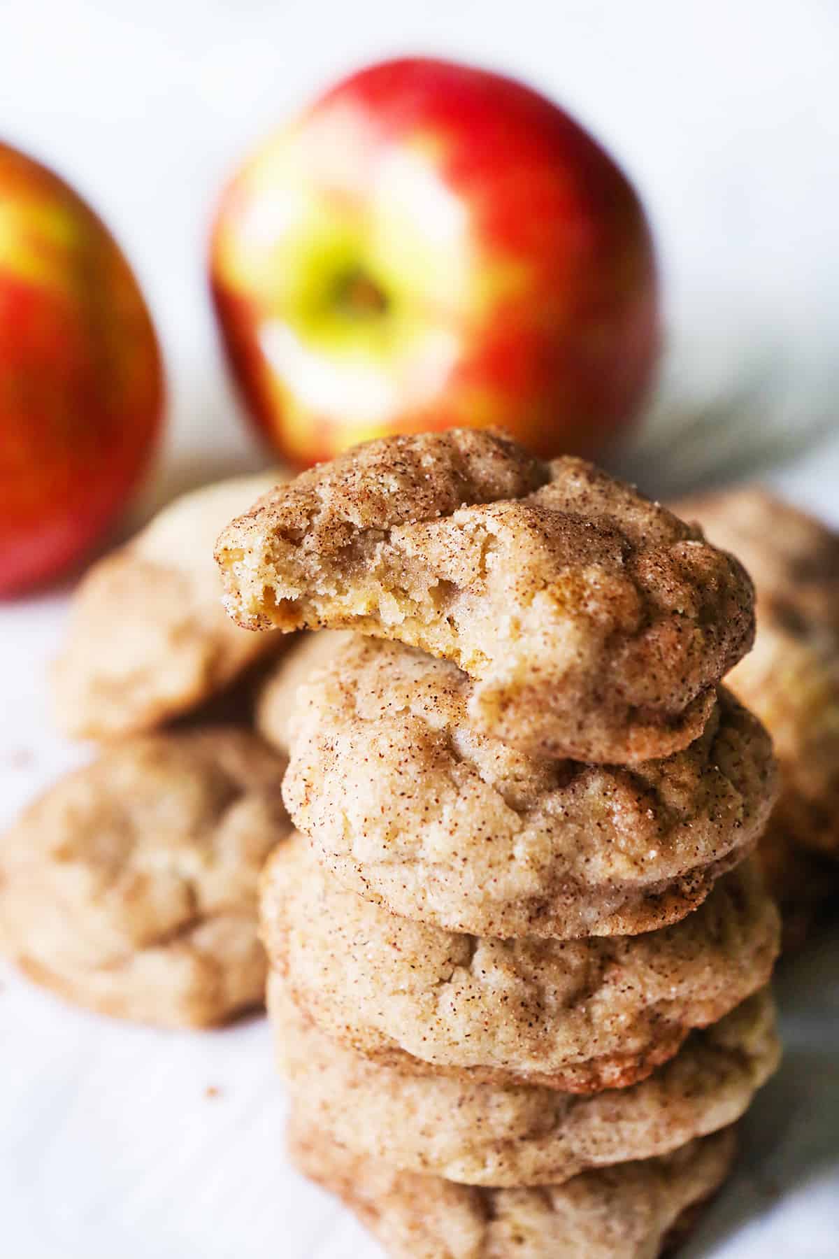 tall stack of apple snickerdoodle cookies with the top one having a bite removed.