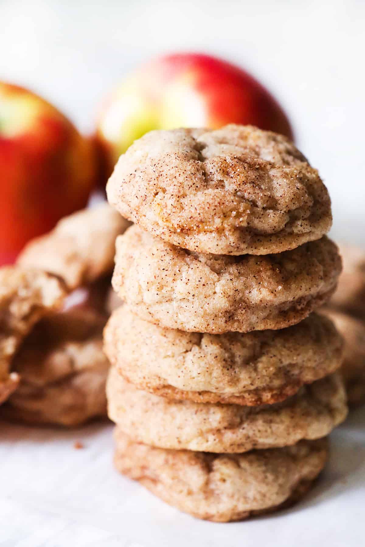 stack of apple snickerdoodle cookies with apples in background.