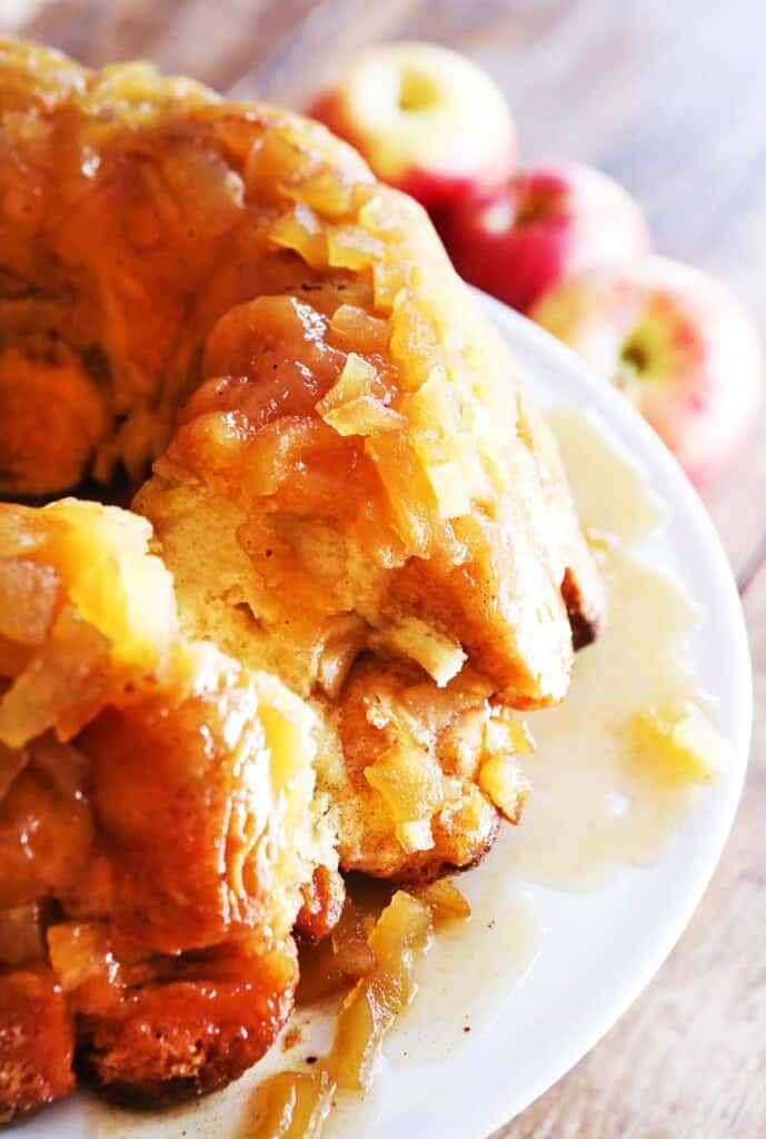 Apple pie monkey bread on a plate with a few bites missing. 