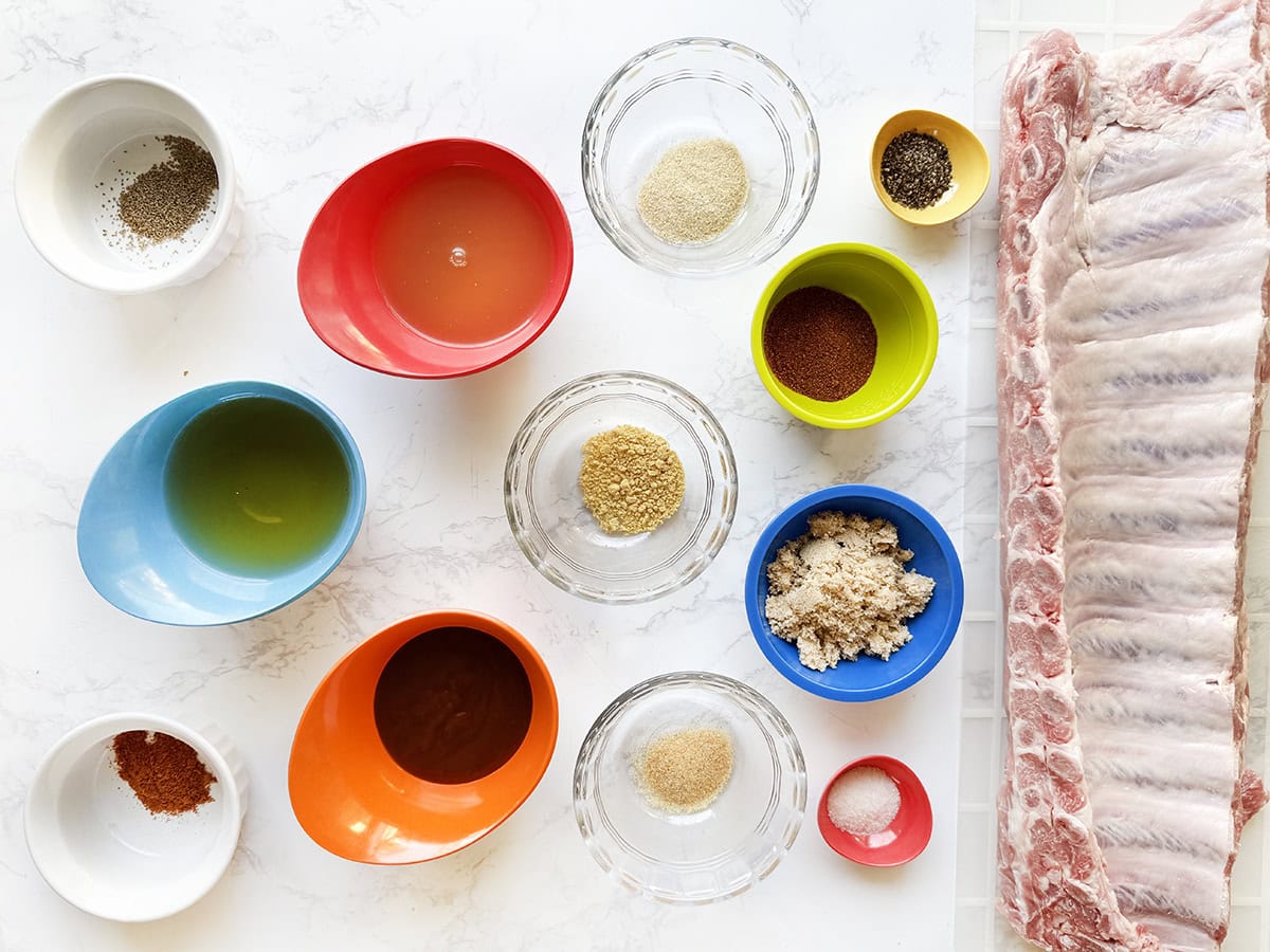 Ingredients to make Instant Pot Pork Ribs in individual bowls, lined up on a white counter.