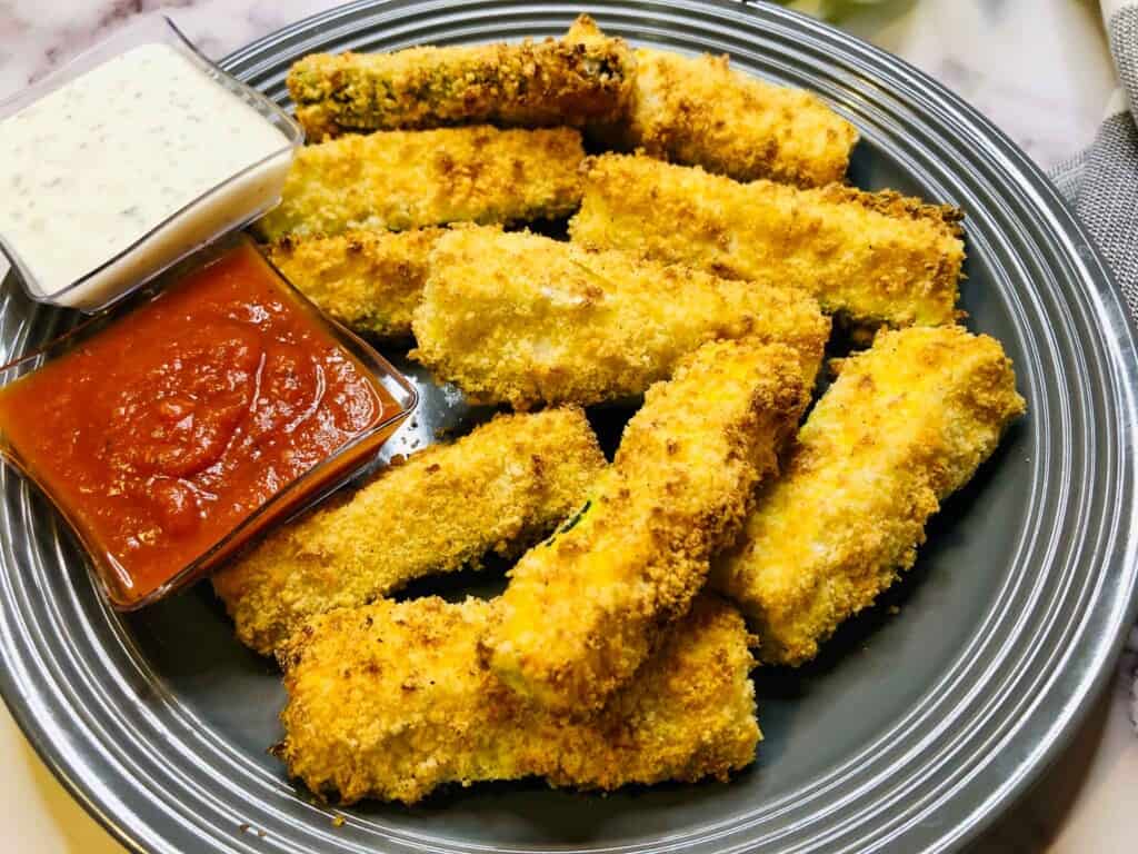 Zucchini fries on a plate with marinara in a small bowl.