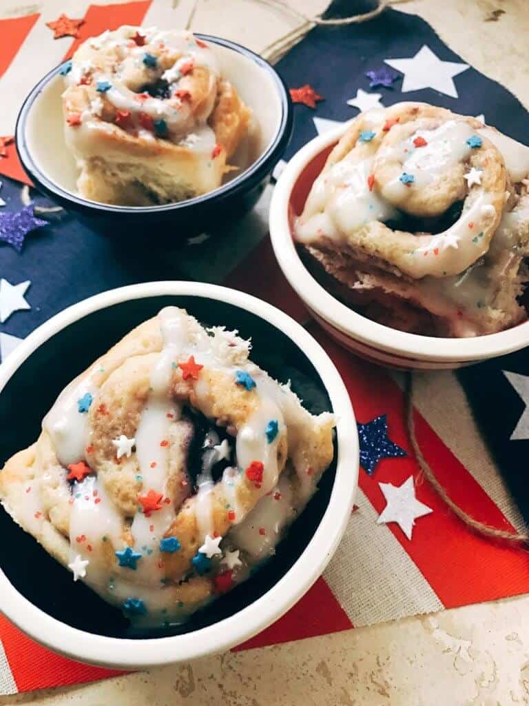 Patriotic berry sweet rolls sitting in individual serving bowls  on a flag placemat.