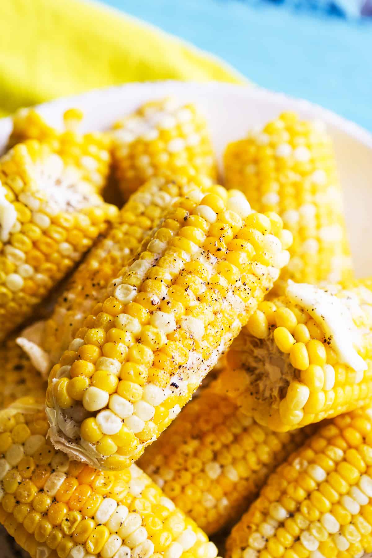 Corn on the cob halves with melted butter and pepper on them. 