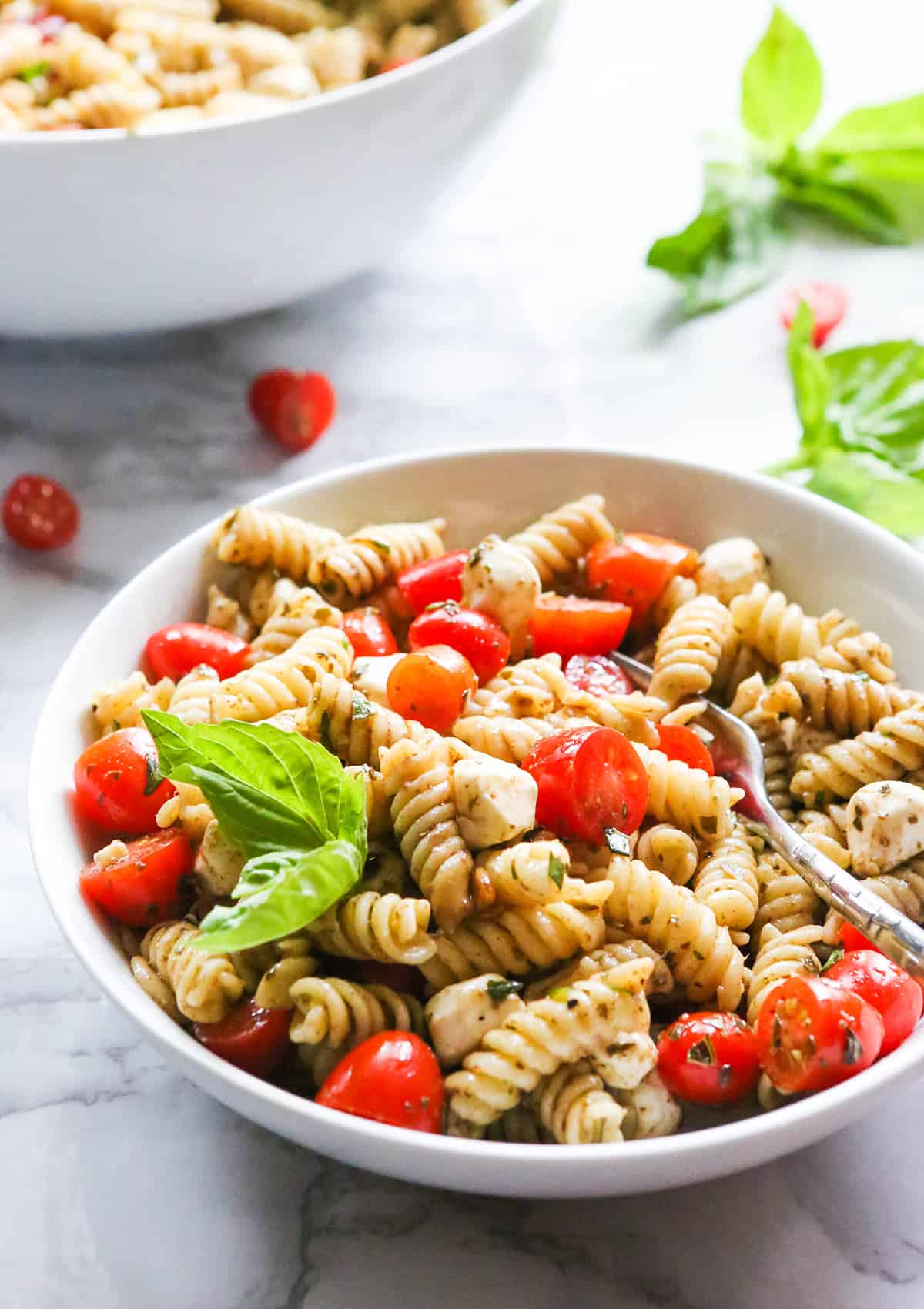 Bowl of caprese pasta salad filled with tomatoes, pasta and mozzarella.