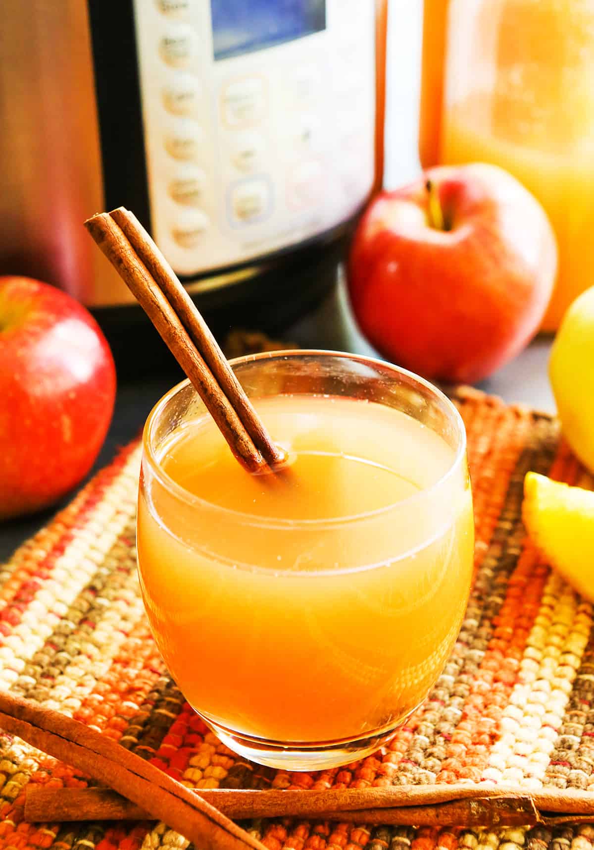 glass of instant pot apple cider with a cinnamon stick in it.