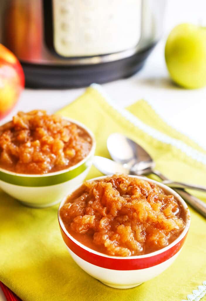 Instant Pot Applesauce served in two small bowls with a spoon next to it. 