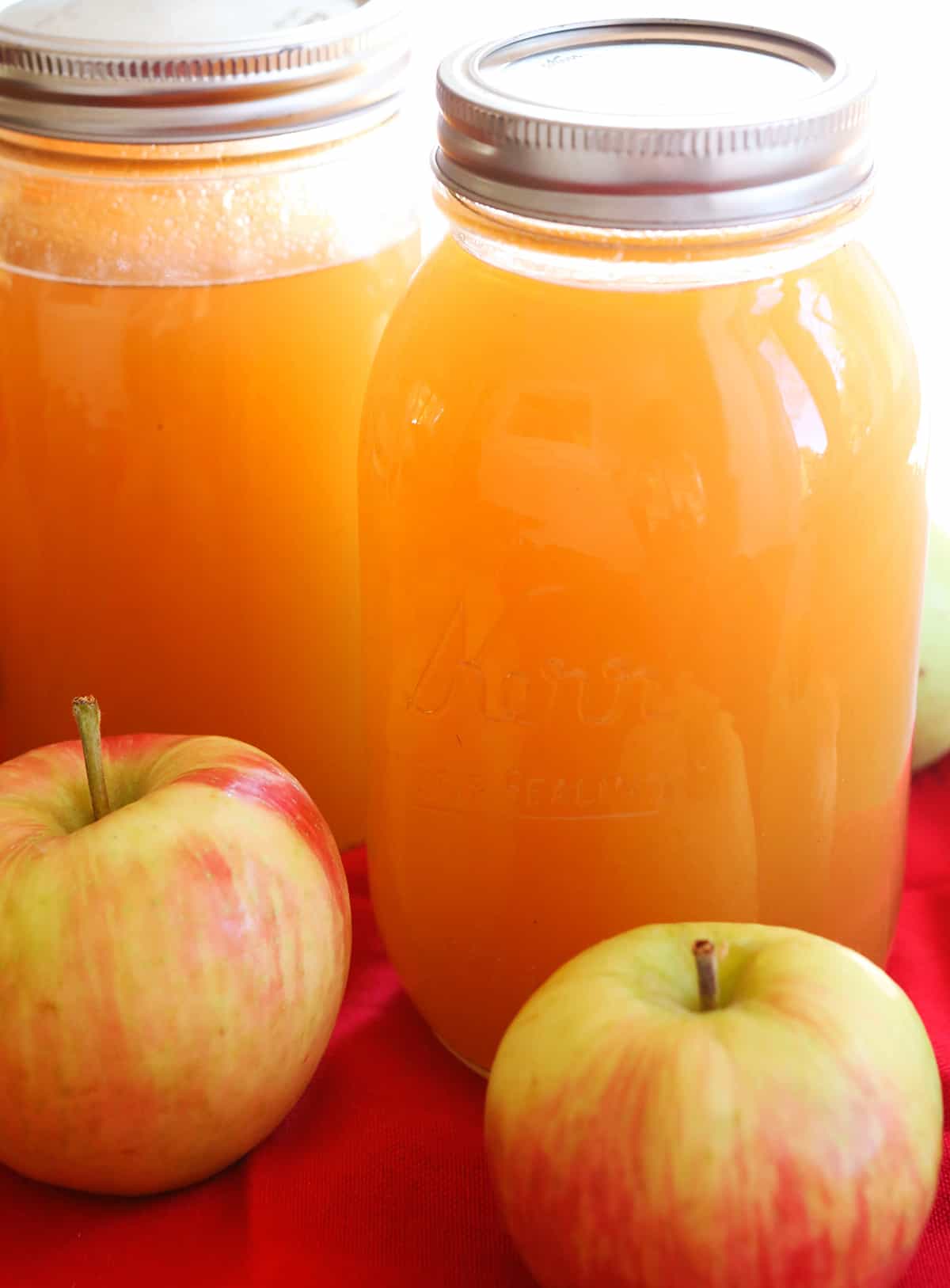quarts of fresh cider with whole apples in front of them.
