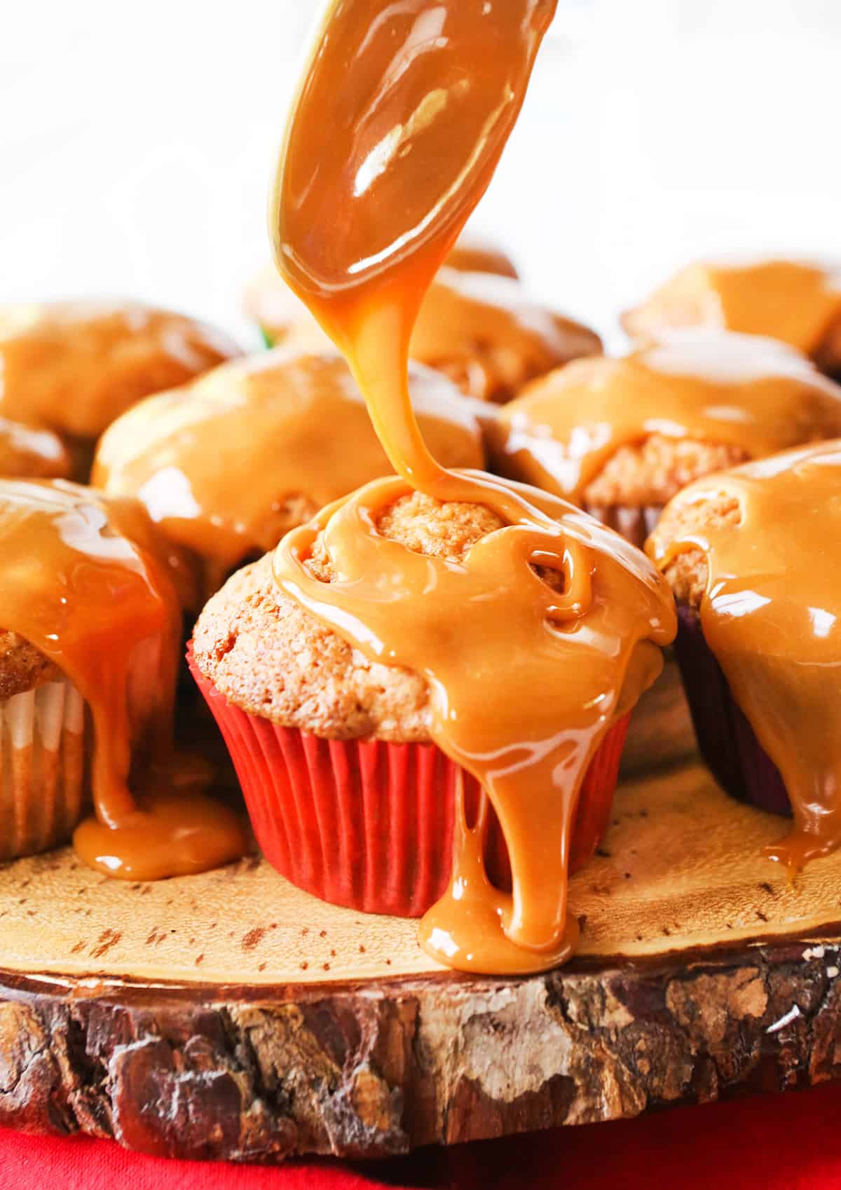 spoon drizzling caramel over cupcakes.