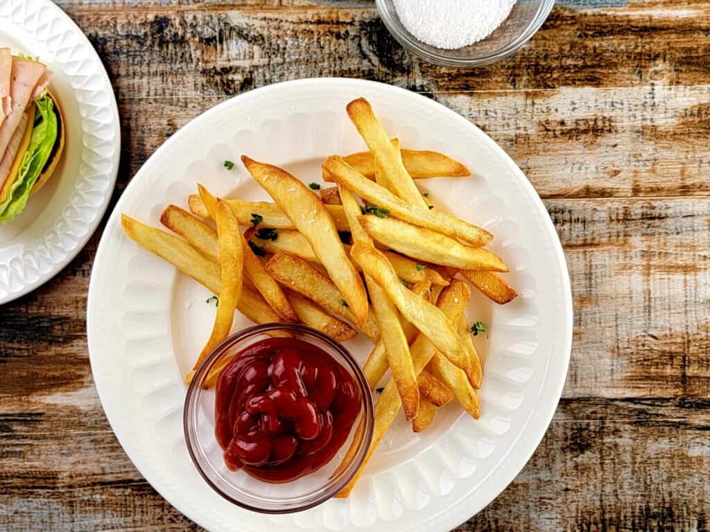 Air fryer french fries with a container of ketchup. 