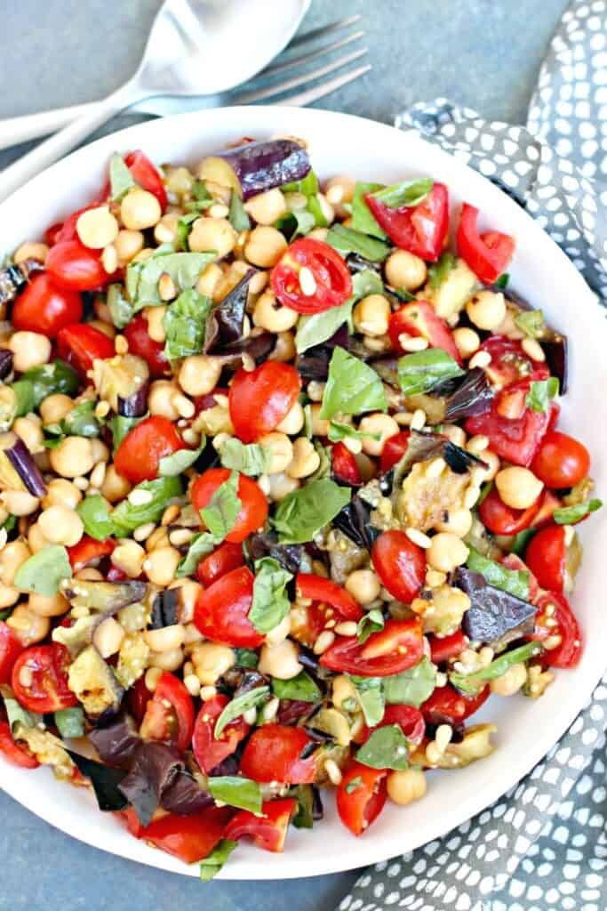 Bowl full of grilled eggplant salad with chickpeas and tomatoes ready to serve on the table. 