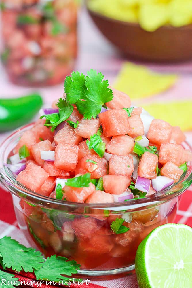 Small glass bowl of watermelon salsa with lime slices and cilantro on top. 