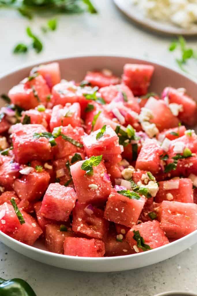 Full bowl of watermelon tomato salad with strip of finely chopped basil on top. 