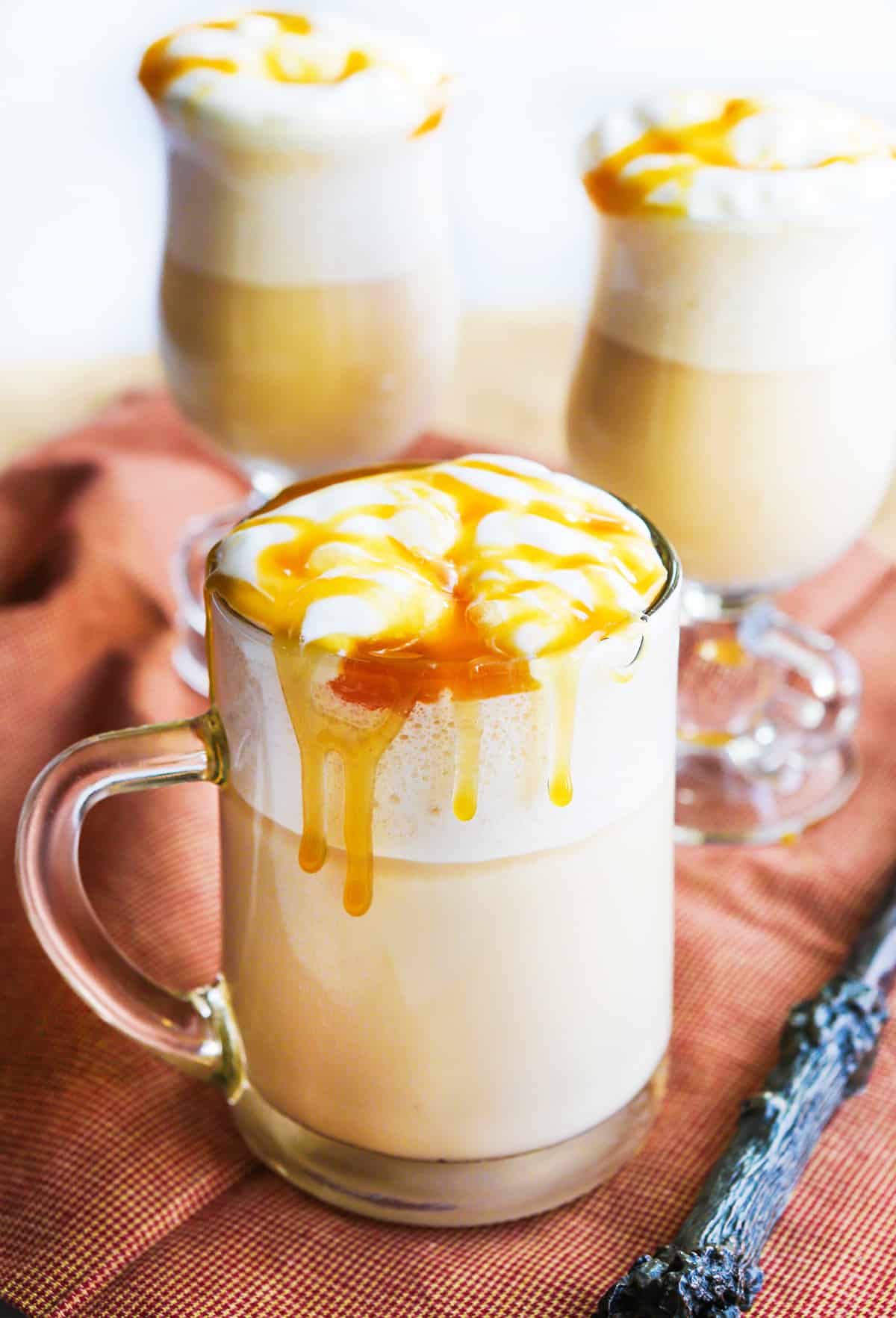 Three mugs of butterbeer with butterscotch topping dripping down glasses.